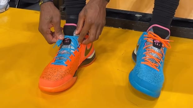 LeBron James ties his blue and orange shoes.